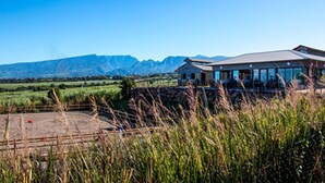 A building with a flat roof and large windows, surrounded by a grassy field and mountains in the background. - Gadiamb City- Glamping (Saint-Pierre)