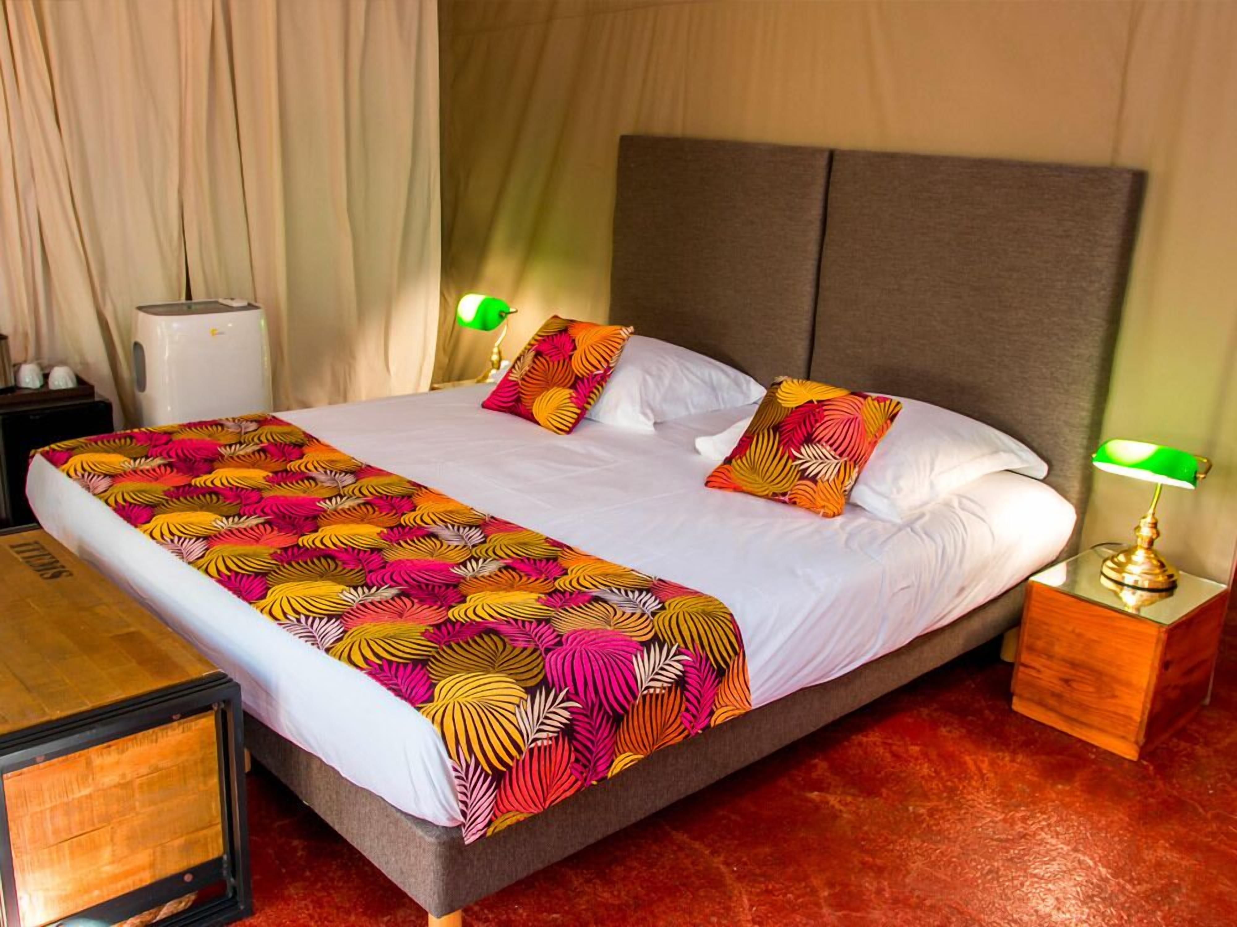 A hotel room with a large bed, two bedside lamps, a nightstand, and a window with curtains.