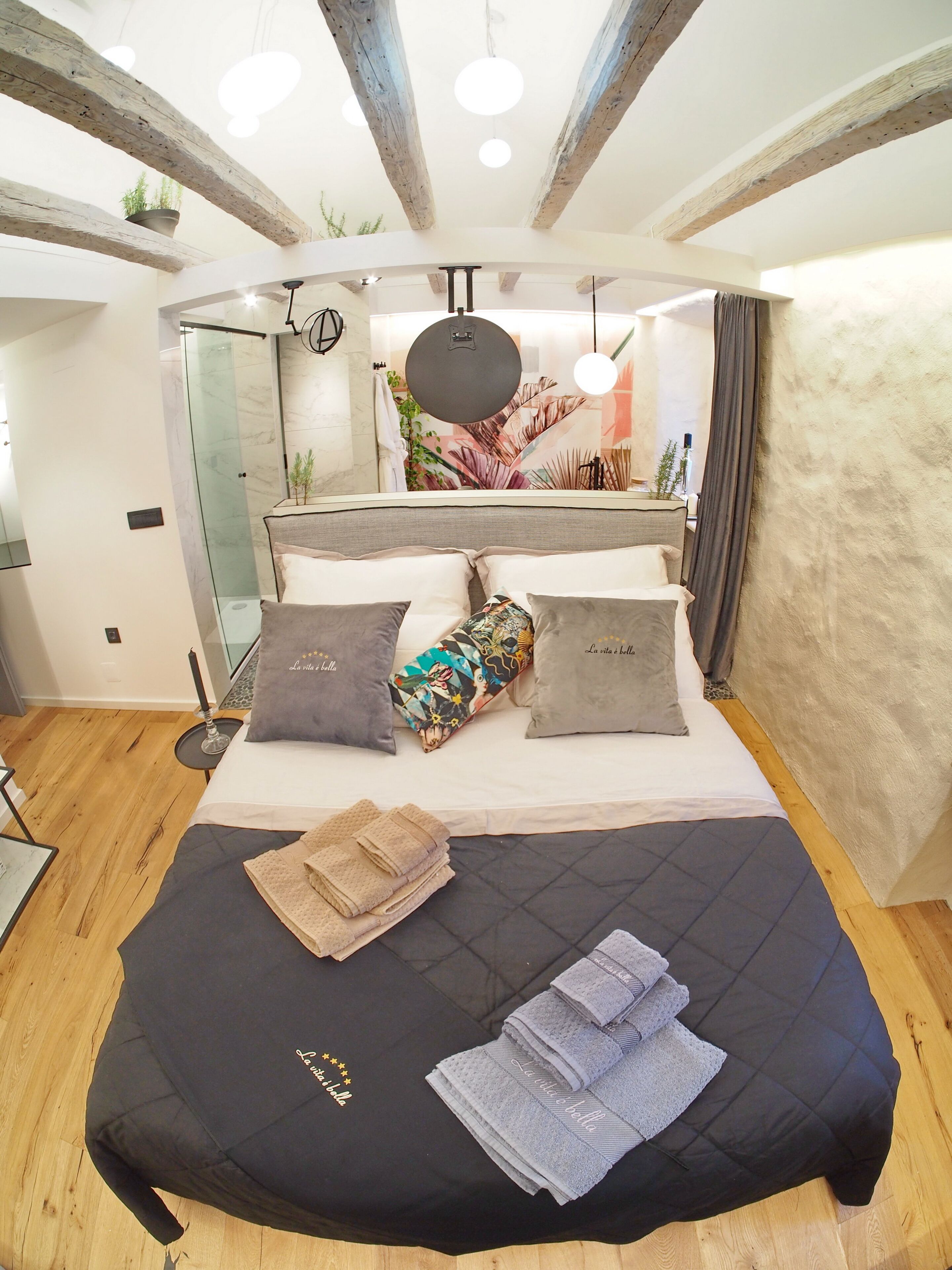 A modern bedroom with a large bed, a bedside table, and a mirror.