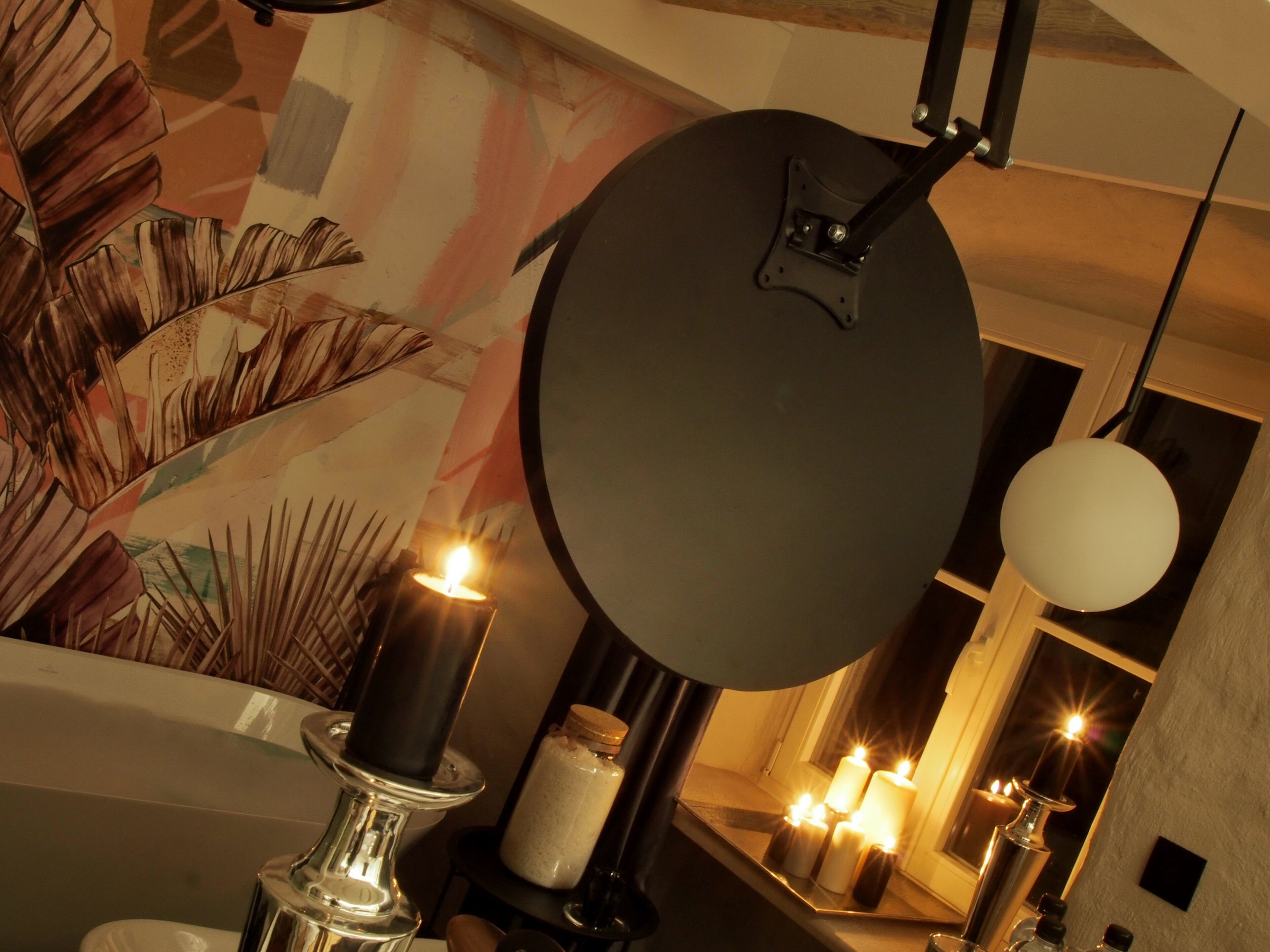 A bathroom with a large mirror, candles, and a decorative plant.