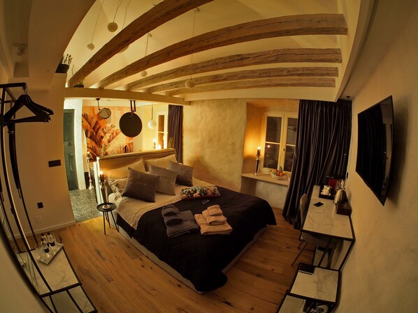 Un dormitorio con cama, mesita de noche y ventana con cortinas.