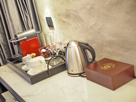 Minibar de um quarto de hotel com cafeteira, copos de vinho e chaleira.