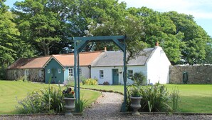 A traditional house with a gravel pathway leading to a wooden archway. - 3 bedroom cottage, with far reaching views of the garden and open countryside. (Whitehills)