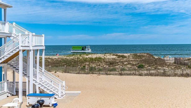 A beach house with a staircase leading to a deck, a pool, and a view of the ocean. - Oceanfront condos with 3 night minimum rentals and linens included! (Ocean City)