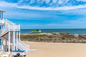 A beach house with a staircase leading to a deck, a pool, and a view of the ocean. - Oceanfront condos with 3 night minimum rentals and linens included! (Ocean City)