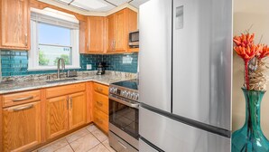 A kitchen with wooden cabinets, a stainless steel refrigerator, and a built-in oven. - Oceanfront condos with 3 night minimum rentals and linens included! (Ocean City)