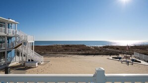 A beach view with a building featuring multiple balconies and a sandy beach area. - Oceanfront condos with 3 night minimum rentals and linens included! (Ocean City)
