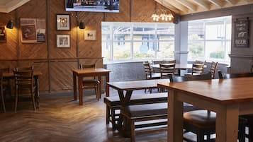 Un restaurante con paredes de madera, ventanas grandes y un televisor fijado a la pared.