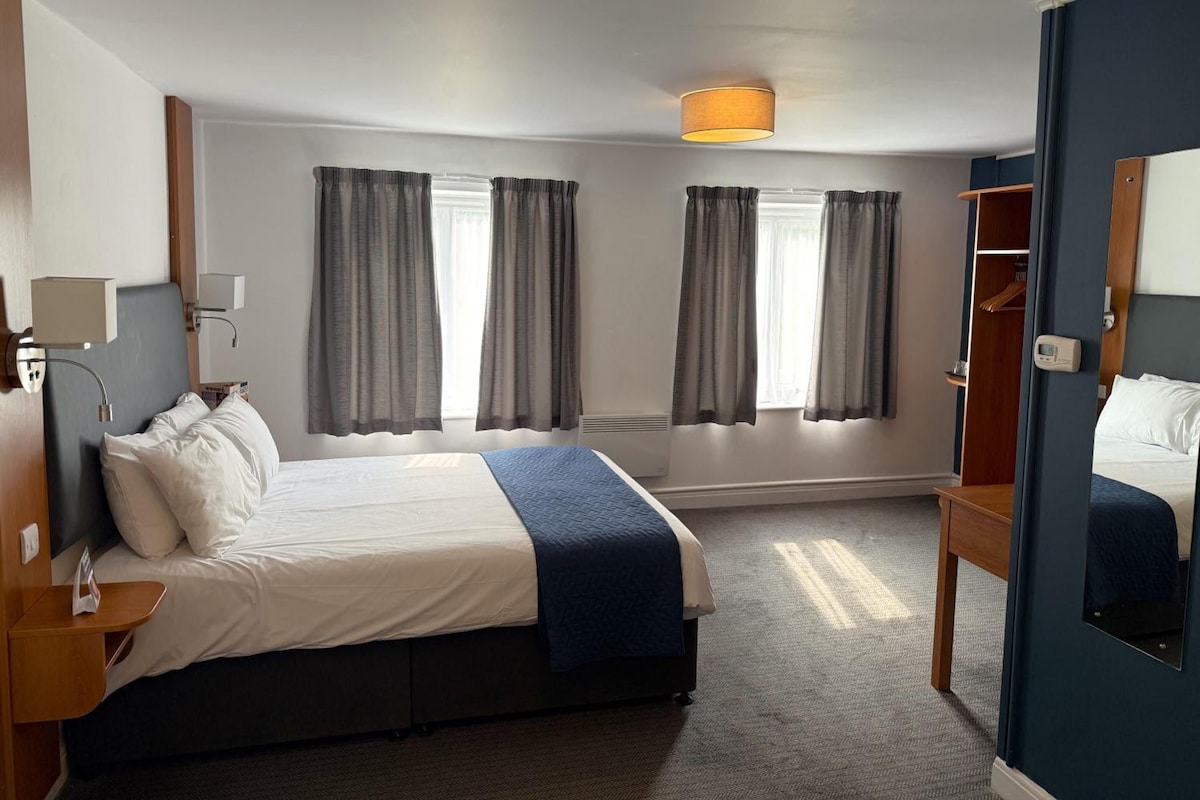 A hotel room with a bed, bedside tables, a wardrobe, and a mirror.