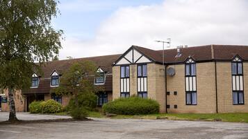 A row of brick buildings with dormer windows and a satellite dish, surrounded by greenery.