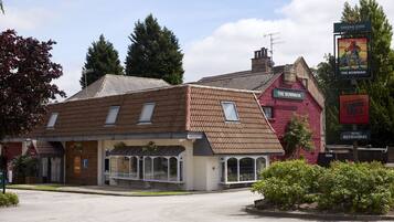 Un bâtiment traditionnel à la façade rouge, avec une enseigne indiquant le pub « The Bowman » et une autre enseigne représentant un « Flaming Grill ».