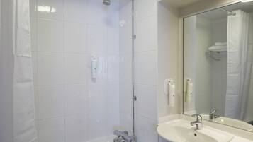 A bathroom with a bathtub, a shower, and a sink with a mirror.