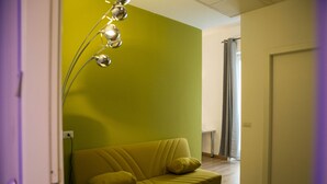 A room with a yellow sofa, a modern floor lamp, and a door. - Palazzo Pasta Malpensa (Gallarate)