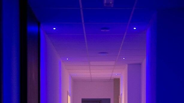 A hallway with a blue-lit ceiling and a wooden floor. - Palazzo Pasta Malpensa (Gallarate)