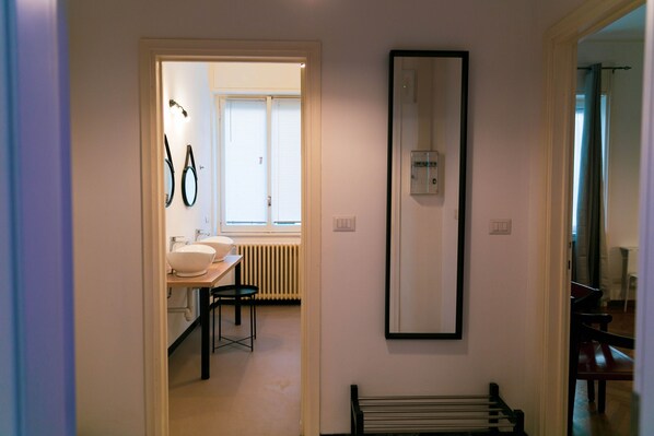A narrow hallway leading to a bathroom with a sink, mirror, and radiator. - Palazzo Pasta Malpensa (Gallarate)