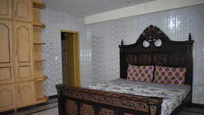 Un dormitorio con estructura de cama de madera, un armario y papel tapiz estampado.
