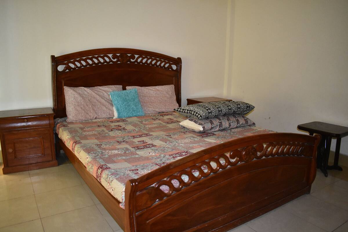 A wooden bed with a quilt, two nightstands, and a small table.