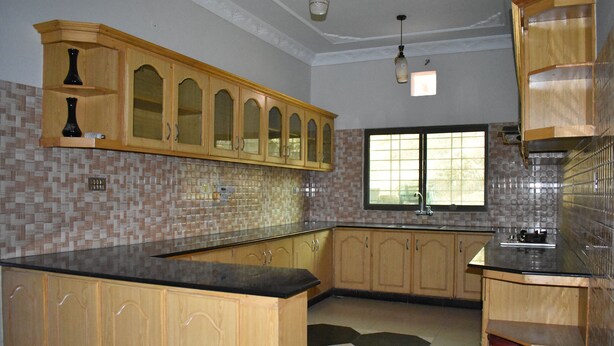 Cocina con armarios de madera, encimera negra y ventana con vistas.