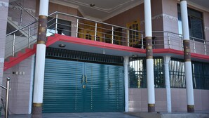 Un edificio con fachada roja y blanca, grandes columnas y un garaje verde cerrado.