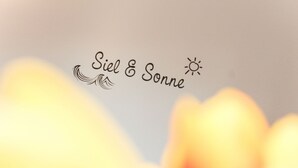 Unscharfer Hintergrund mit dem Text 'Siel & Sonne' und einem Sonnensymbol.