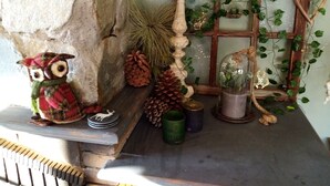 A rustic shelf with a wooden owl, pine cones, a glass dome with plants, and a rustic wall.