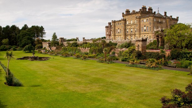 A large, historic building with a well-maintained lawn and garden.