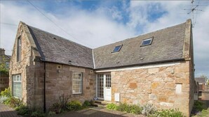 A stone house with a sloped roof, a front door, and a small porch area.