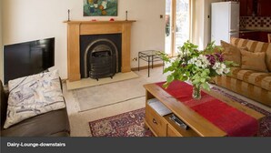 A living room with a fireplace, a television, a sofa, a coffee table, and a dining area with a table and chairs.