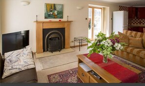 A living room with a fireplace, a television, a sofa, a coffee table, and a dining area with a table and chairs.