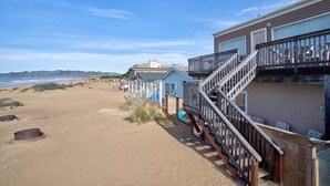 A beachfront property with a wooden staircase leading to a balcony, a sandy beach, and a clear view of the ocean. - Steps from the Sand! Spacious Beach Home with Amazing Ocean Views! (Oceano)