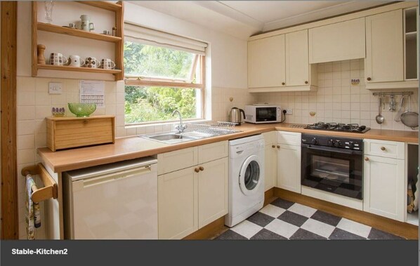 Compact kitchen with modern design, gas stove, microwave, and washing machine.