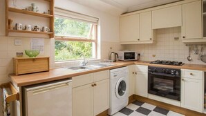 Una cocina con armarios blancos, lavadora, microondas y estufa.