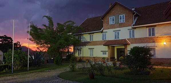 A two-story house with a paved driveway and a garden.
