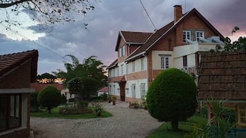 Stunning two-story house with a brick and plaster exterior, set amidst beautifully maintained gardens and a charming cobblestone pathway.