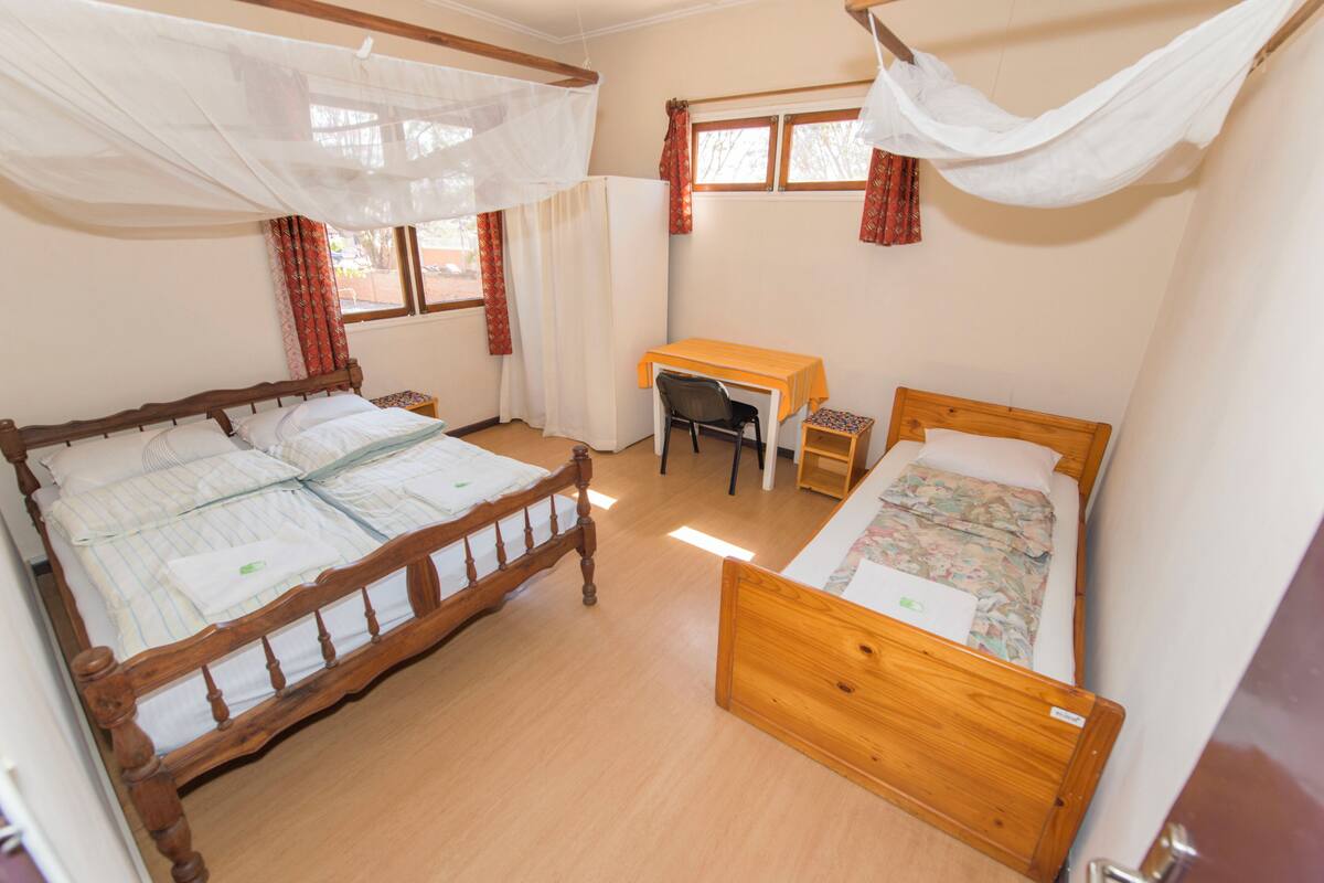 Ein Schlafzimmer mit zwei Holzbetten, einem Schreibtisch und einem Stuhl.