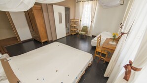 Una camera d'albergo con un letto grande, un armadio in legno, un tavolino con un vaso di fiori e una sedia.