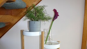 Une étagère en bois avec trois étagères blanches, chacune supportant une plante et un vase.