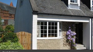 Une maison avec une grande fenêtre, une clôture en bois et un mur en pierre.