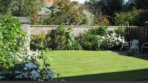 Un jardin bien entretenu, avec une pelouse, diverses plantes à fleurs et une clôture en bois.