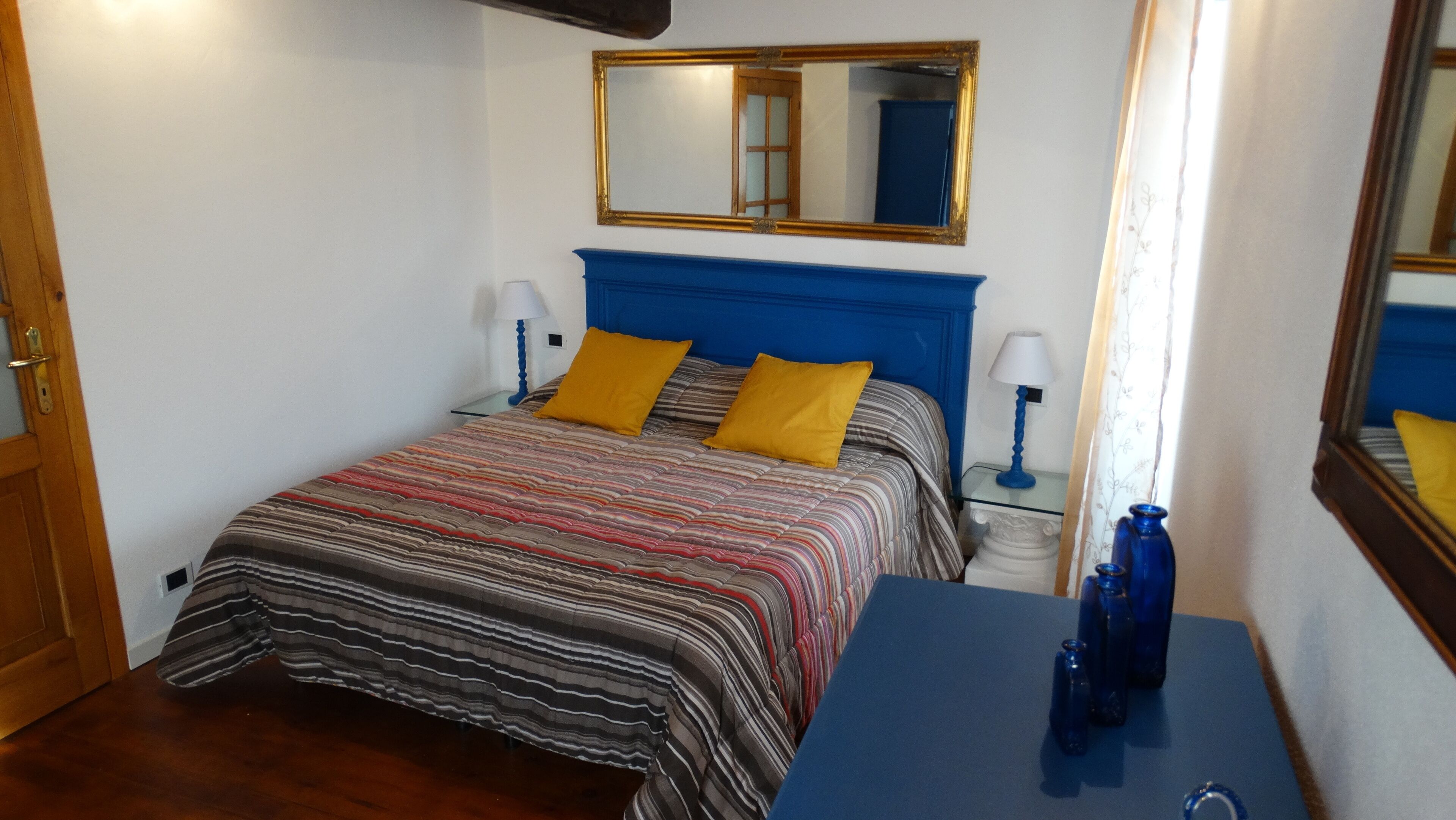 Une chambre à coucher avec un lit, deux lampes de chevet, un miroir et une commode.