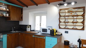 A kitchen with wooden cabinets, a microwave, a cutting board, and a plate rack. - LUCAS LUXURY HOUSE .. (LUNI)