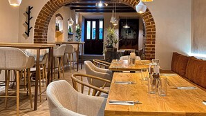 A restaurant with wooden tables and chairs, a brick archway, and hanging pendant lights. - Hermannstadt House (Sibiu)