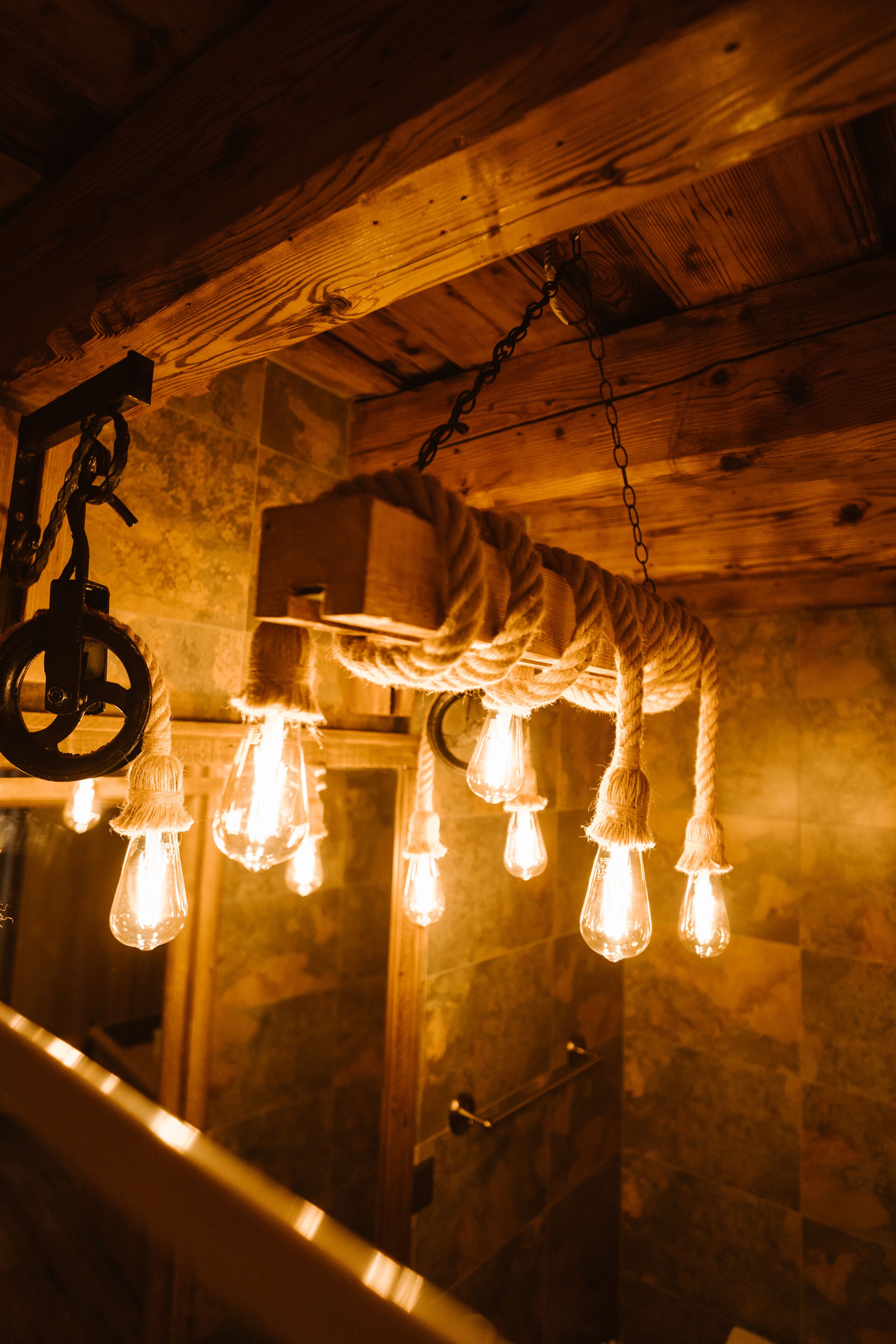 Un plafond en bois rustique avec des poutres apparentes et un luminaire suspendu à une corde.
