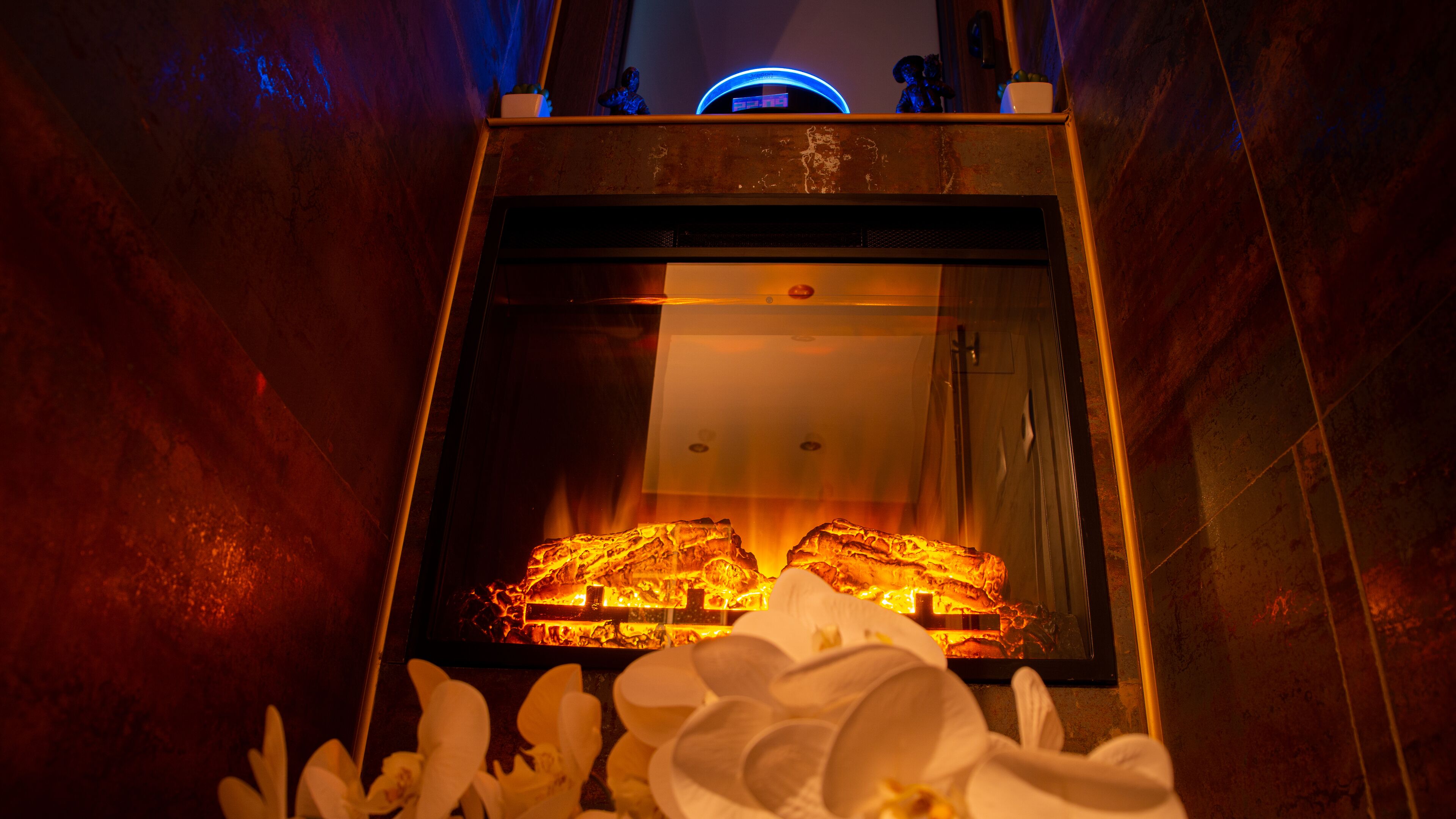 A fireplace with a glass front, surrounded by white flowers.