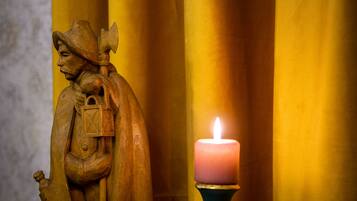 Eine Holzstatue mit einer Kerze davor.