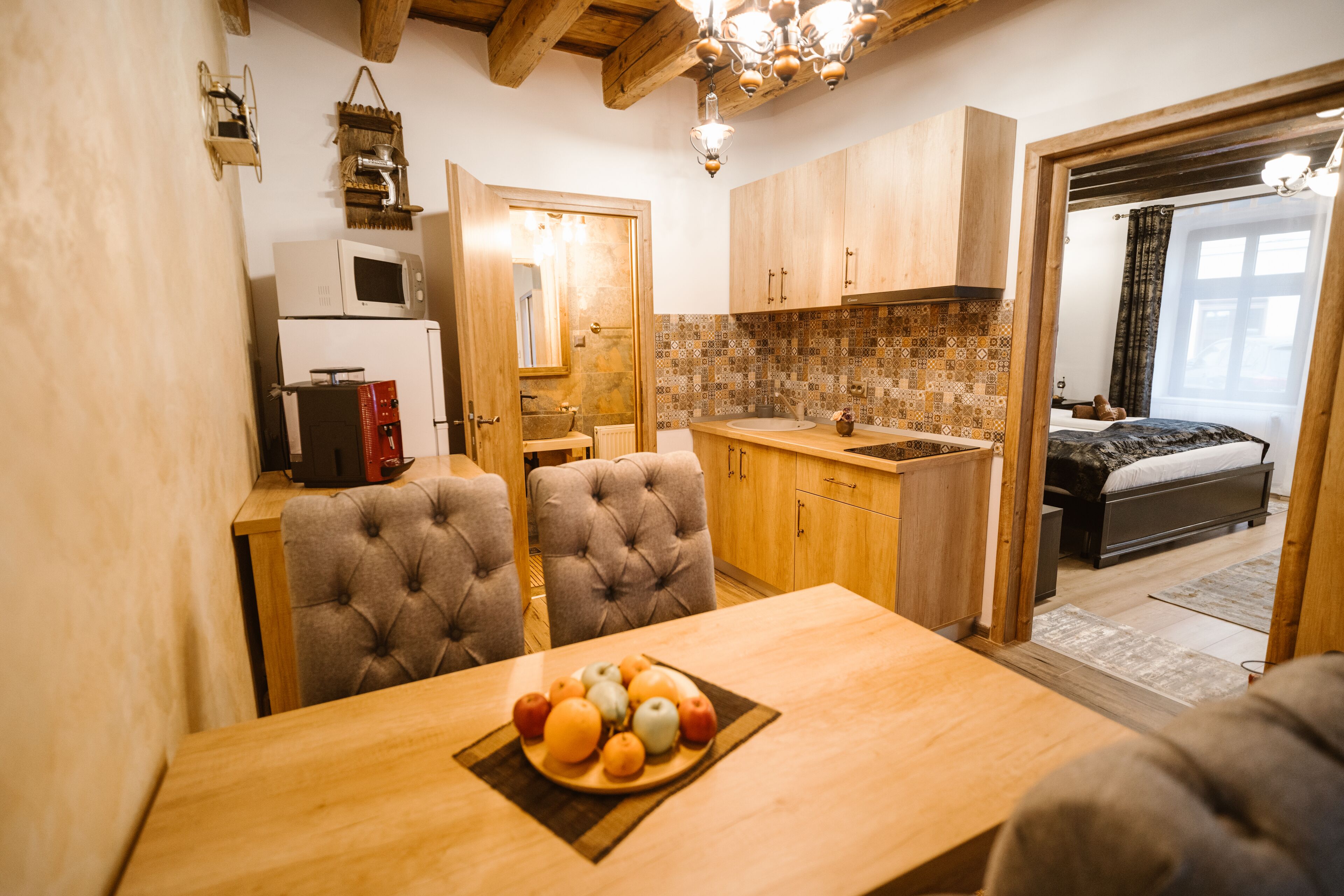 A compact kitchen with wooden cabinets, a microwave, and a dining area with a table set for a meal.