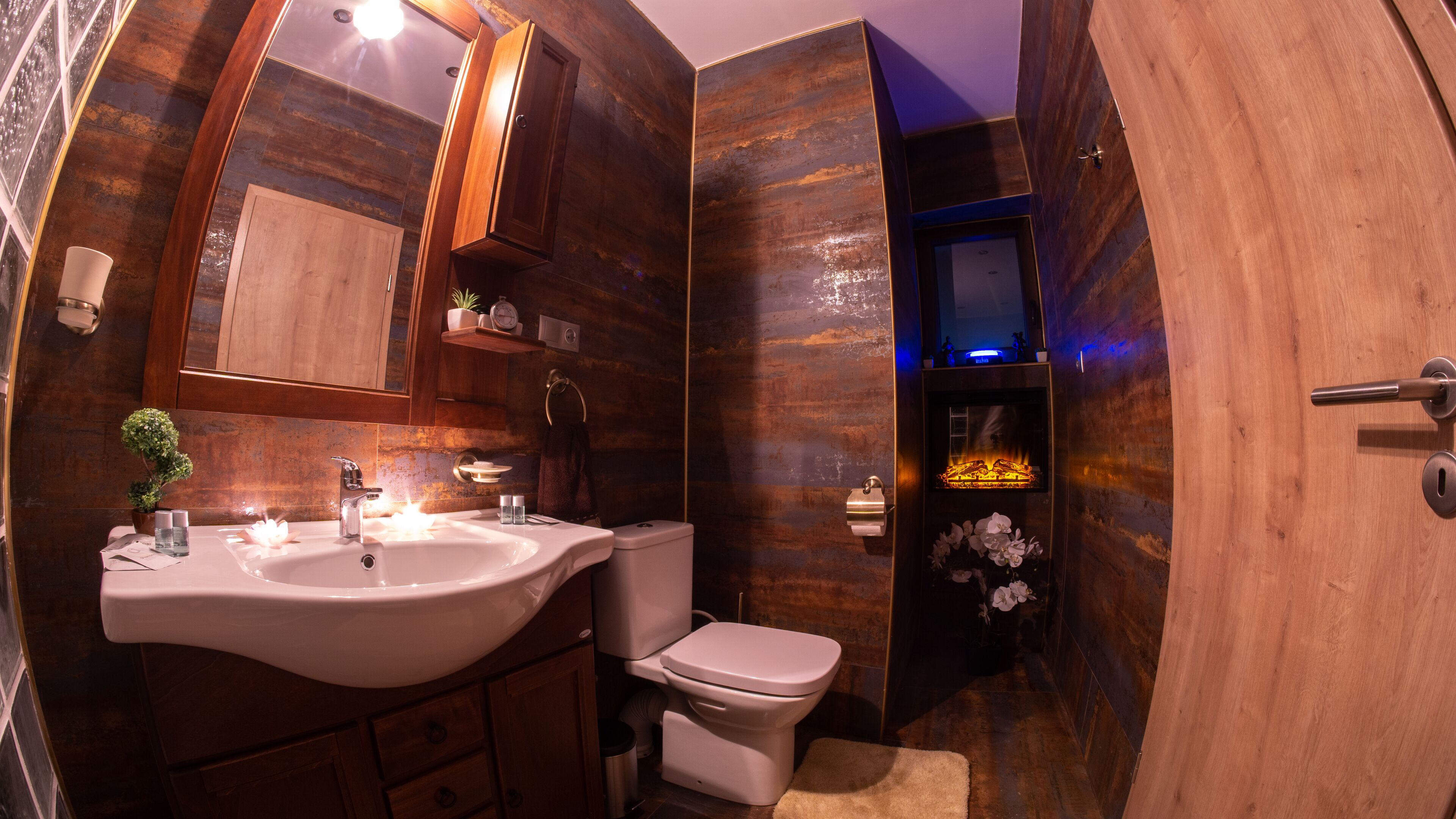 A bathroom with a wooden vanity, a sink, a toilet, and a mirror.