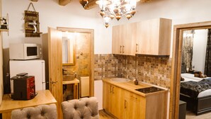 A compact kitchen with wooden cabinets, a microwave, and a fruit bowl on the table. - Hermannstadt House (Sibiu)