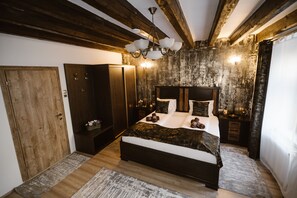 Une chambre avec un plafond en bois, un grand lit, des tables de chevet et une commode.