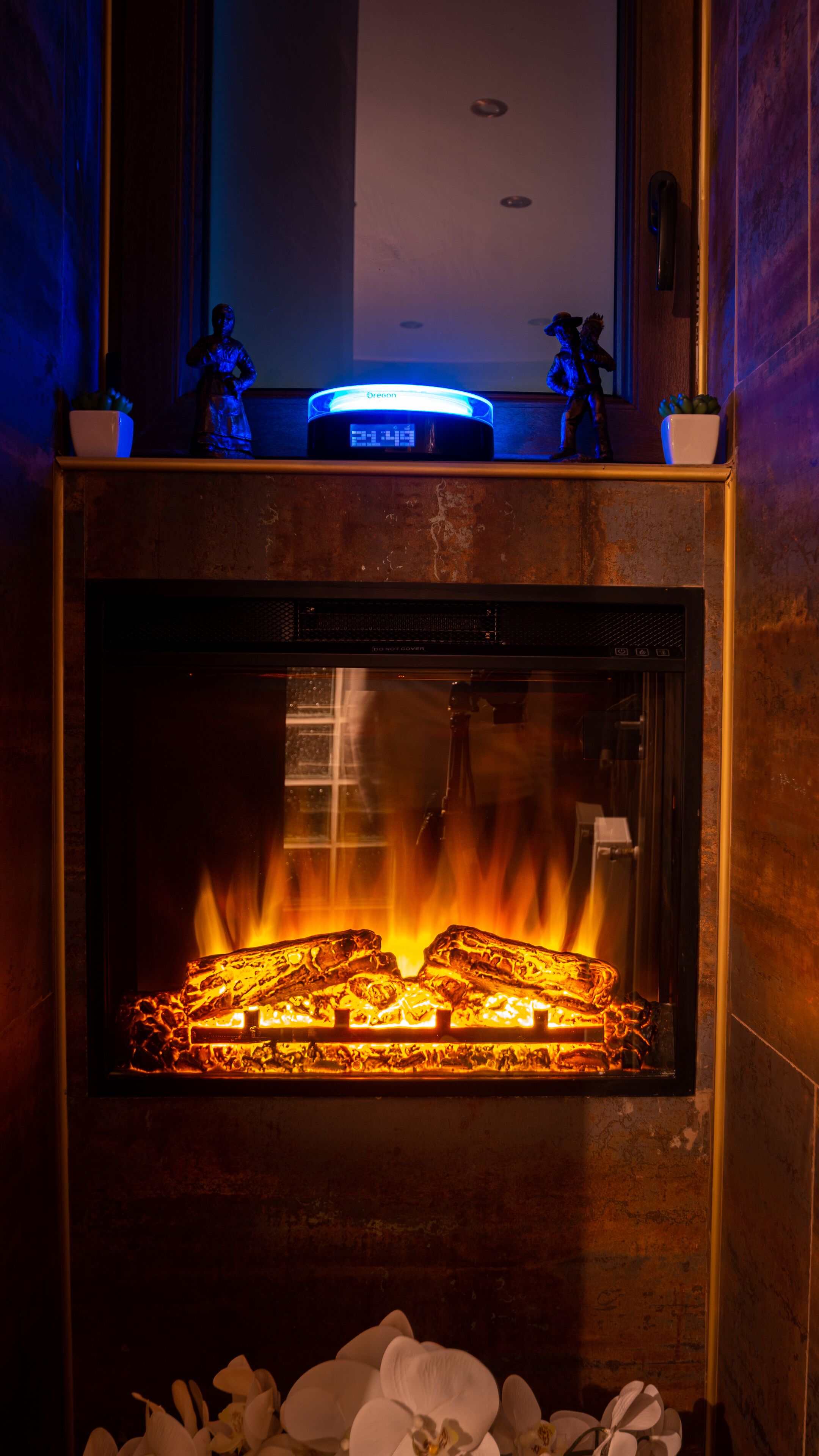 A fireplace with a digital clock above it, surrounded by decorative items.